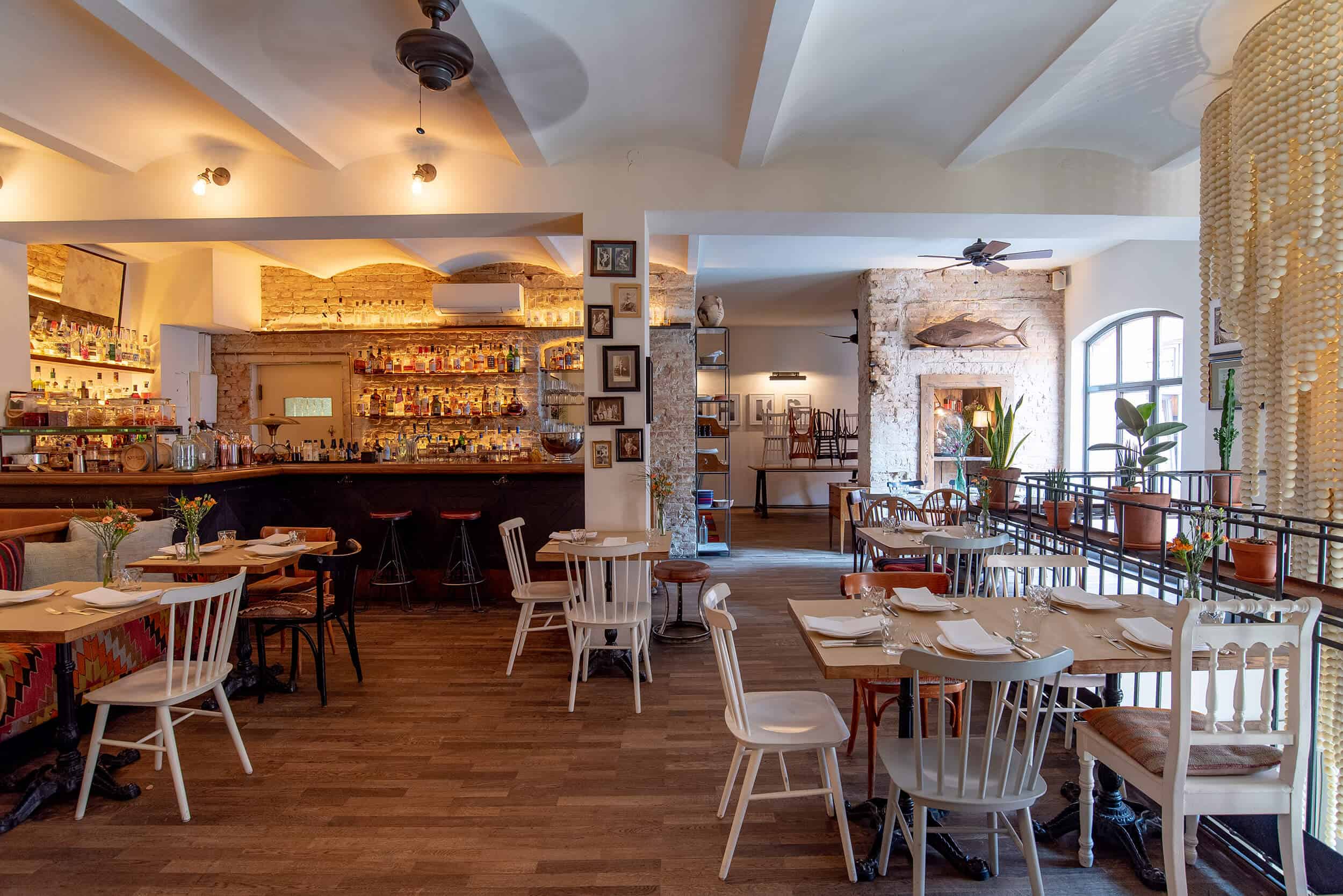 Interior view of a spacious, stylishly furnished restaurant on the upper floor with a well-stocked bar, various seating areas and decorative elements.